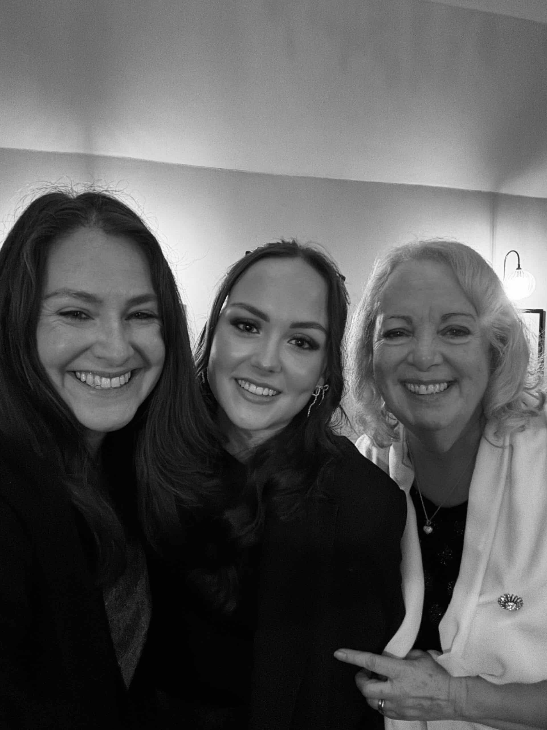 Three women smiling together in a black and white photo.