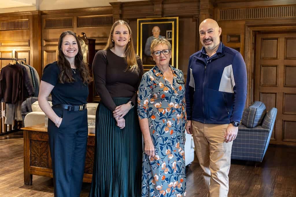 Group of four professionals at networking event in a wood-paneled room.