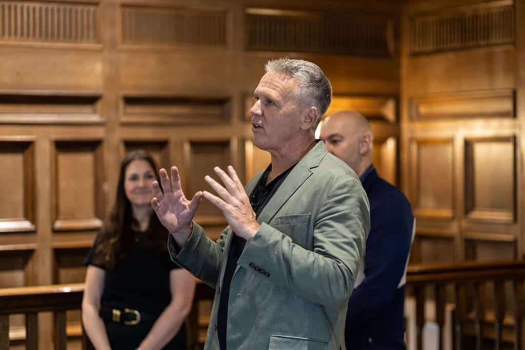 Man speaking at networking event with two women listening.