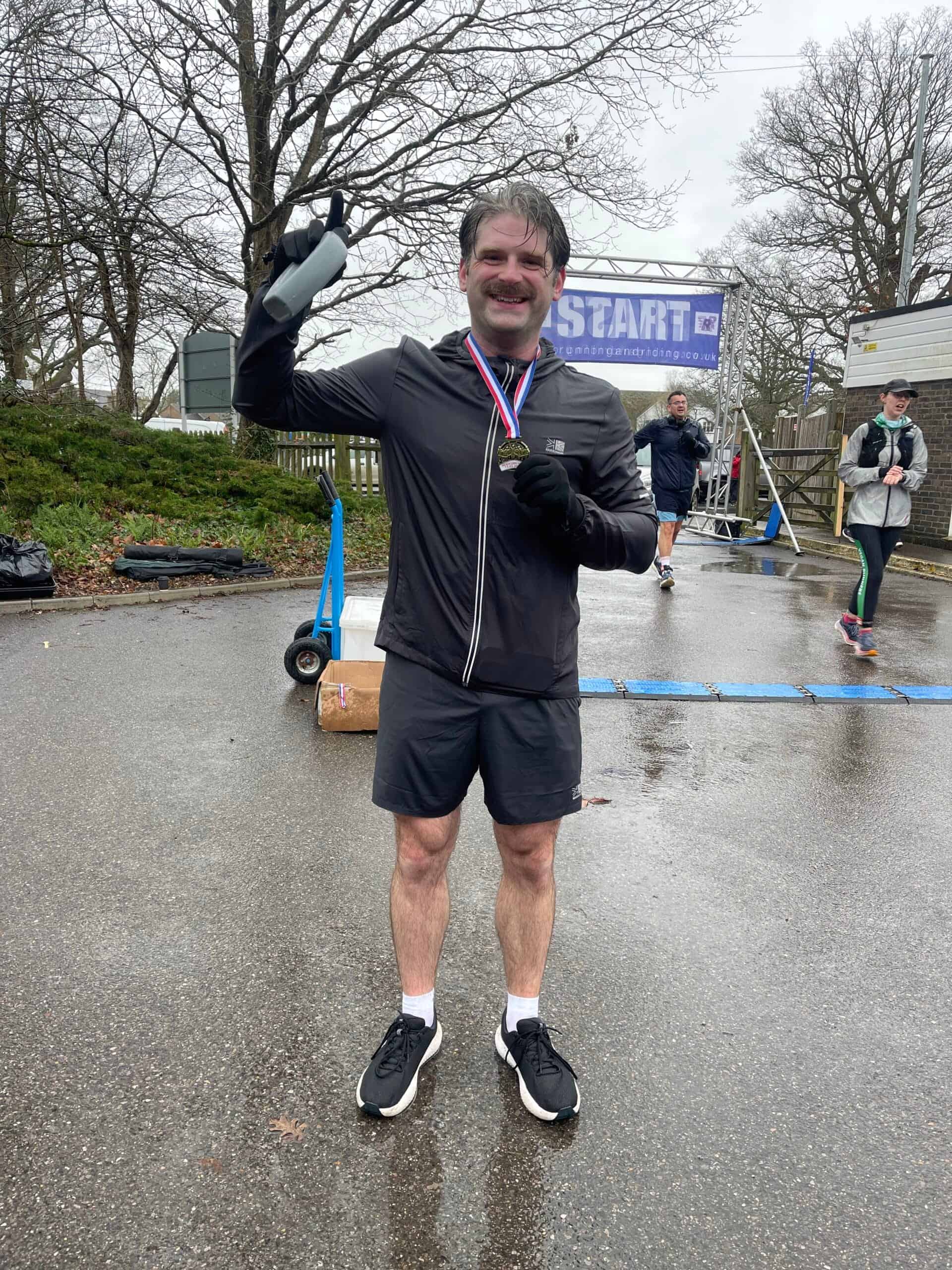 Runner with medal at Headcorn Half Marathon on a rainy day.