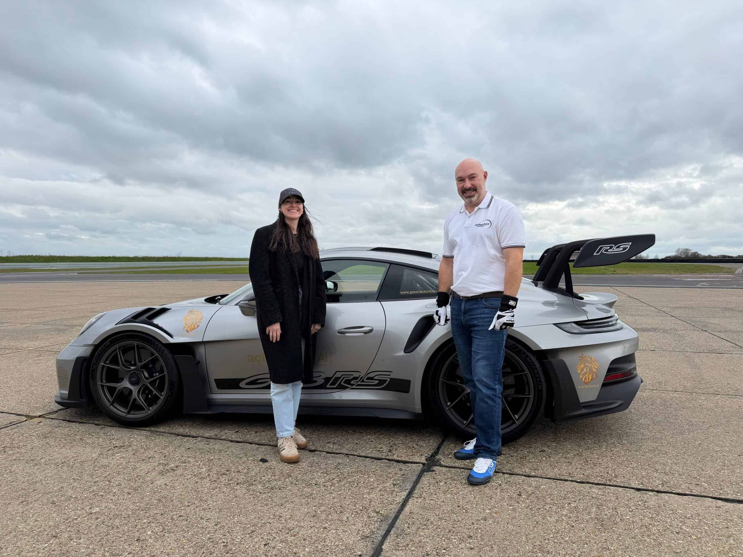 Two people standing beside a grey race car at Bedford Autodrome.