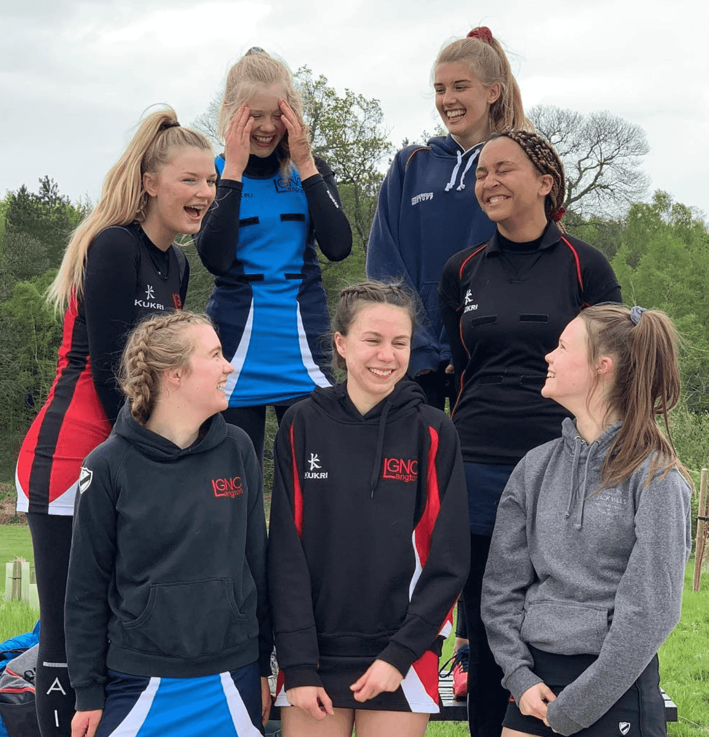 Netball team of young women in sportswear smiling outdoors.