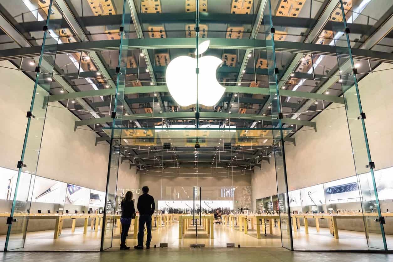 Apple Store entrance with large glowing Apple logo and glass facade.