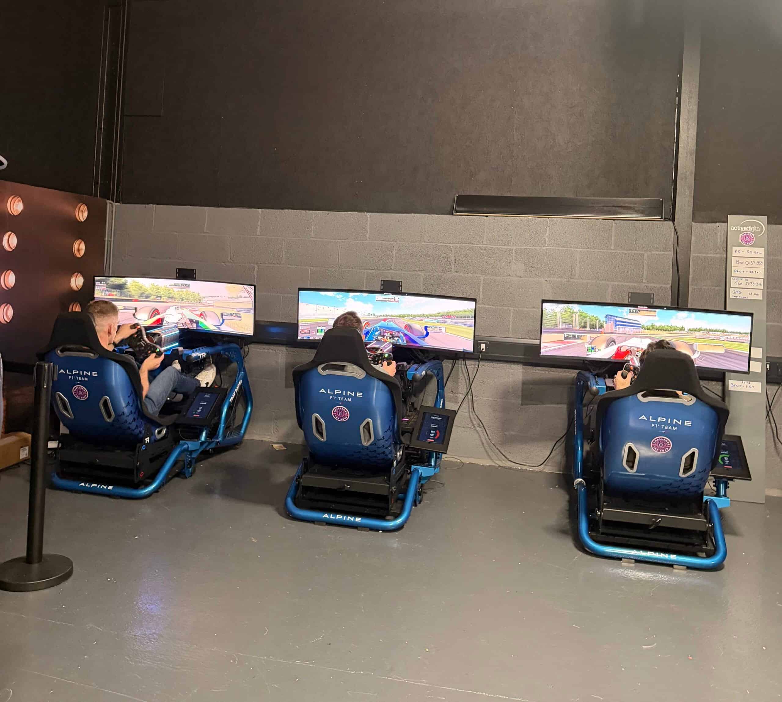 Three people playing racing simulators at an event.
