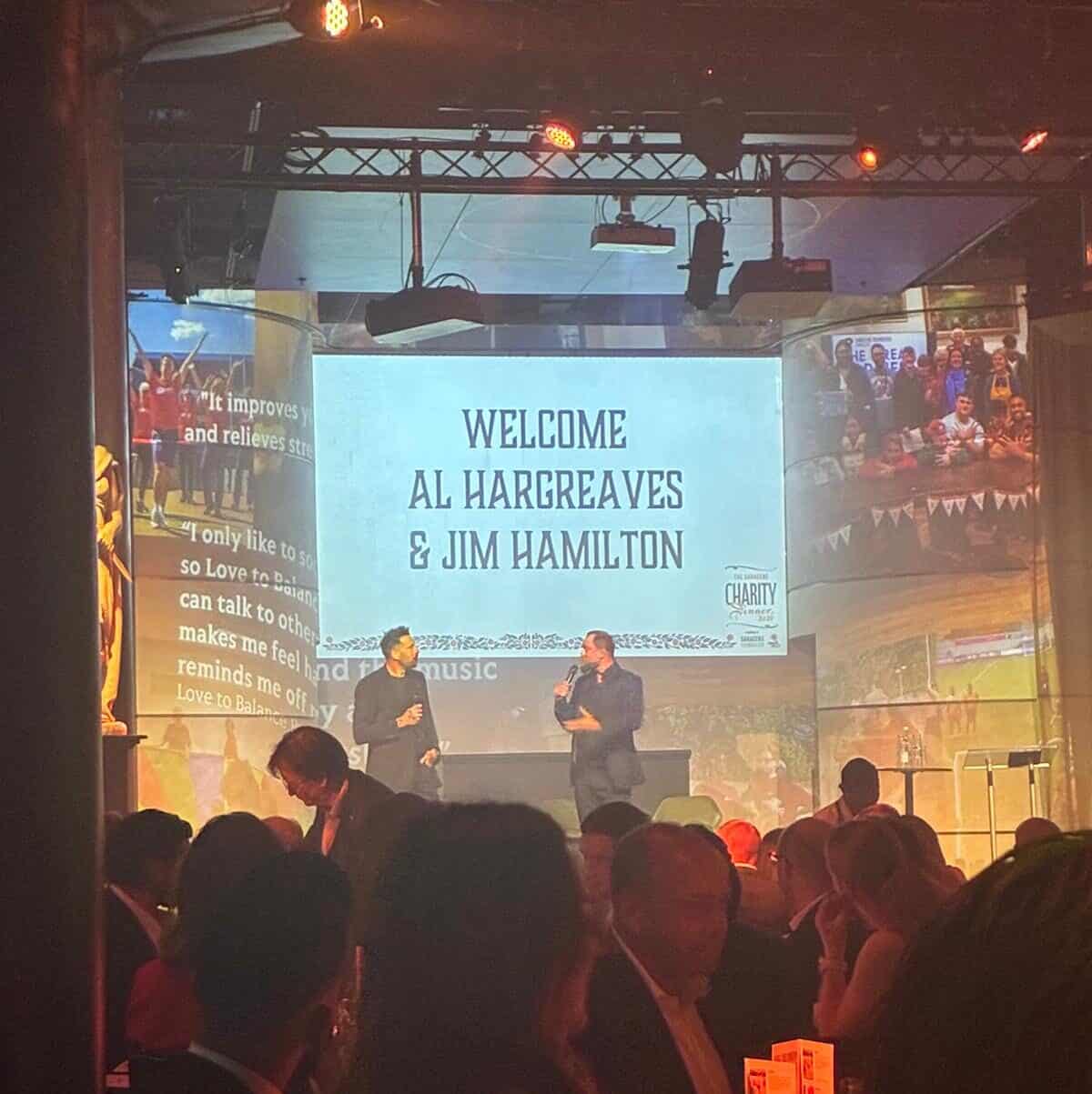 Two speakers on stage at the Saracens Foundation Charity Dinner 2026.
